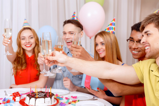 Young people celebrating a birthday sitting at the table - Фото, изображение
