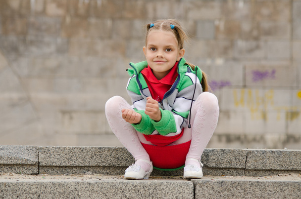 Altı yaşındaki bir kız granit merdivenlerinde oturur - Fotoğraf, Görsel