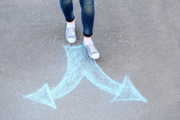 Female feet and drawing arrows on pavement background - Фото, изображение