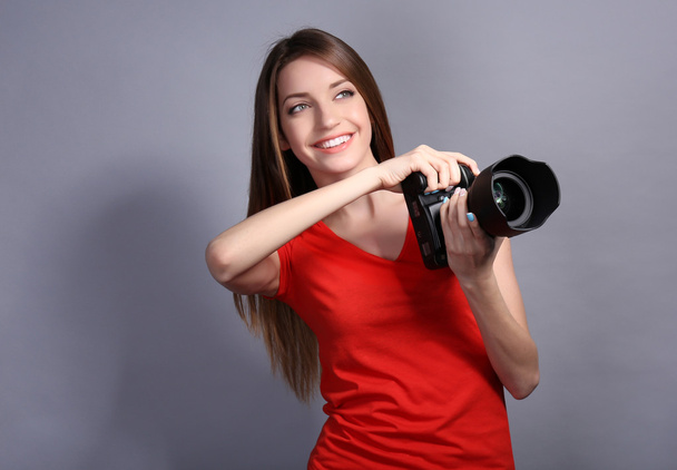 Young female photographer taking photos on grey background - Zdjęcie, obraz