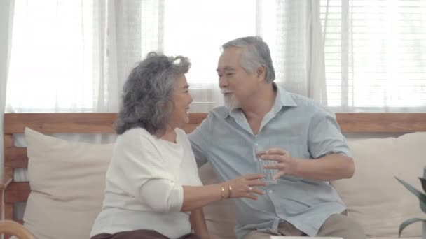 Ázsiai család töltenek időt nyaralni otthon együtt. Nagyszülők könyvet olvasnak otthon a nappaliban. - Felvétel, videó