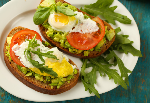 Tasty sandwiches with egg, avocado and vegetables on plate, on wooden background - Zdjęcie, obraz