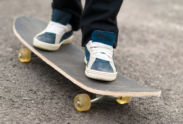 Skateboarder rides on a skateboard feet in sneakers. - Фото, зображення