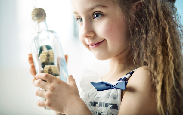 Маленькая девочка держит бутылку с кораблем
  - Фото, изображение