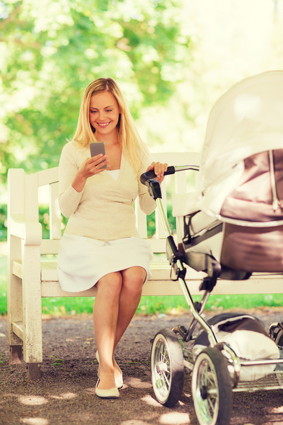 happy mother with smartphone and stroller in park - Foto, Imagem