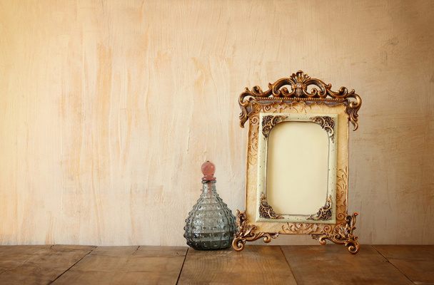 Image of victorian vintage antique classical frame and perfume bottle on wooden table. filtered image - Foto, Bild