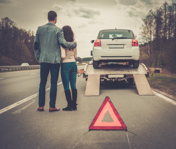 Couple near tow-truck picking up broken car  - Photo, Image