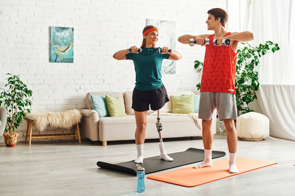 A couple works out together at home, with one partner using a prosthetic leg. - Foto, Imagen
