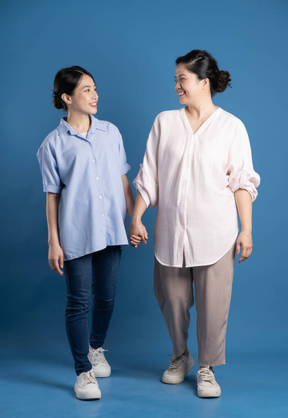 Изображение азиатской матери и ребенка, позирующих на синем фоне - Фото, изображение