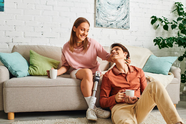 Una pareja relajándose en casa en un sofá, compartiendo un momento de intimidad. - Foto, Imagen