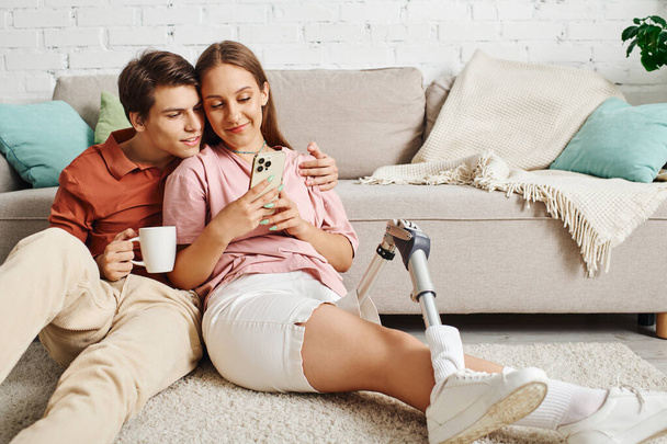 Frau mit Beinprothese trinkt Kaffee mit Freund und schaut aufs Handy. - Foto, Bild