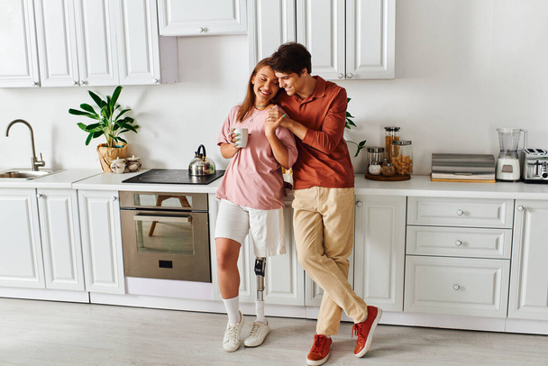 Eine Frau mit Beinprothese genießt einen Kaffee mit ihrem Freund in der Küche. - Foto, Bild