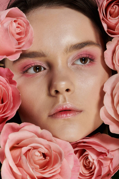 Een close-up portret van een vrouwengezicht omringd door roze rozen. - Foto, afbeelding