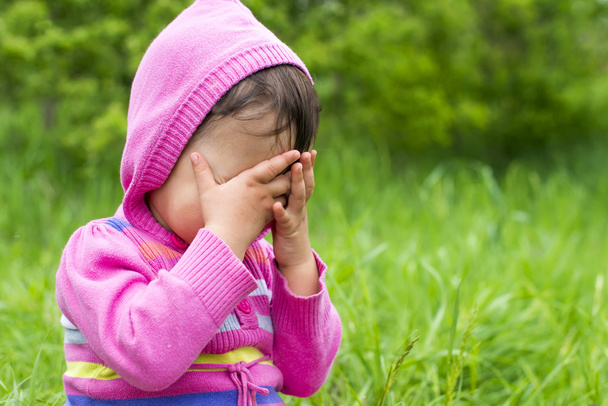 klein meisje speelt verstoppertje verbergen gezicht - Foto, afbeelding