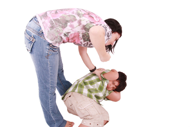 mujer golpeando a un hijo que cringes, aislado sobre fondo blanco - Foto, afbeelding