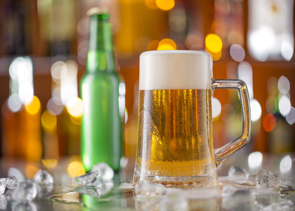 Бутылка пива со стеклом на барной стойке
 - Фото, изображение