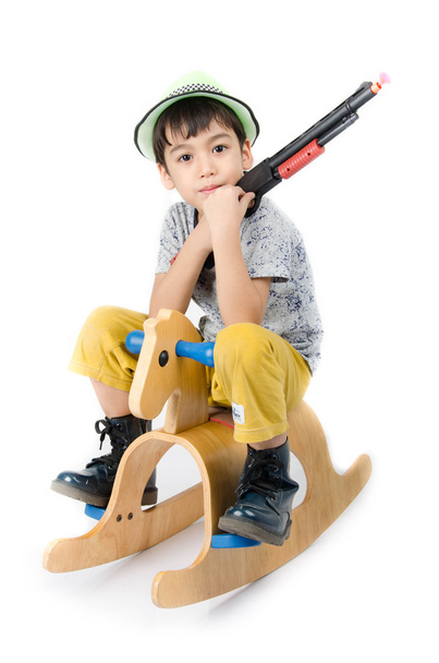 Маленький мальчик с деревянной лошадью и оружейной игрушкой на белом фоне
 - Фото, изображение