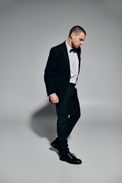 A man in a tuxedo walks confidently with his hand in his pocket. - Fotografie, Obrázek