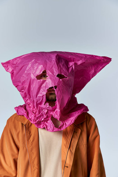 Een man met een roze plastic zak als masker. - Foto, afbeelding