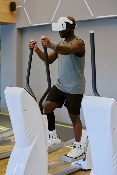 African American sportsman doing cardio while he playing VR game - Foto, Imagen