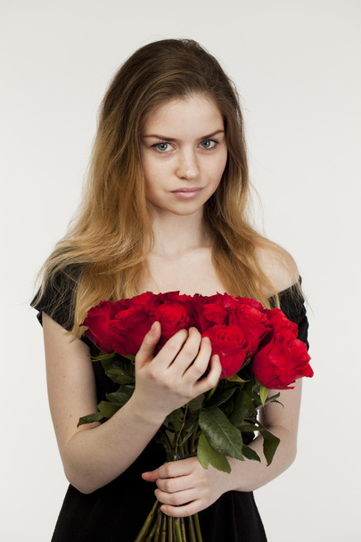 Portrait of a young beautiful girl with a bouquet of red roses - Foto, immagini