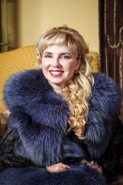 woman in a fur coat on a chair - Foto, Imagem