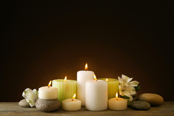 Beautiful composition with candles and spa stones on dark background - Фото, изображение