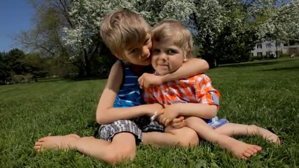 Kaksi onnellista pikkuveljeä halaamassa vihreällä ruoholla.
 - Materiaali, video