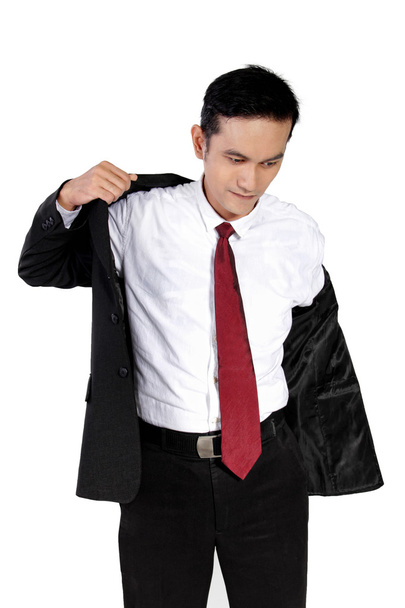 Nuori liikemies pukemassa pukua, eristyksissä valkoisella
 - Valokuva, kuva