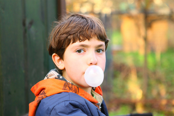 Preteen knappe jongen met kauwgom bubble close-up counrty po - Foto, afbeelding