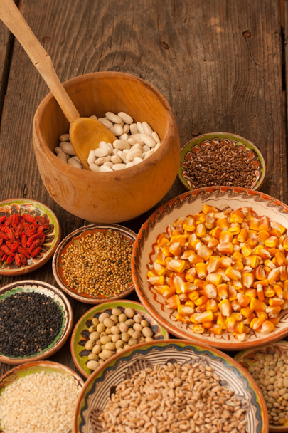 Vari chicchi di grano in piccoli piatti di argilla su corteggiamento naturale testurizzato
 - Foto, immagini
