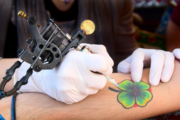 Tatuaje mostrando el proceso de hacer un tatuaje. Diseño del tatuaje en forma de trébol de cuatro hojas
 - Foto, imagen