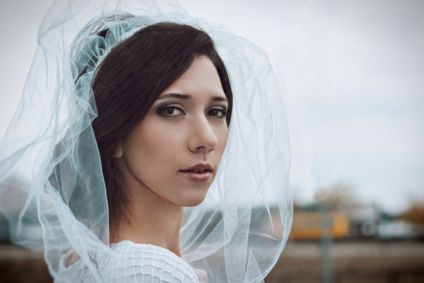 Close-up πορτρέτο της νύφη όμορφη νεαρή γυναίκα σε λευκό πέπλο και φόρεμα. Φωτογραφία γάμου. Ρομαντικό ύφος. Ευτυχία. Μόδας μακιγιάζ γάμου φως καπνιστή μάτια μαργαριταρένια μπεζ και καφέ αποχρώσεις. - Φωτογραφία, εικόνα