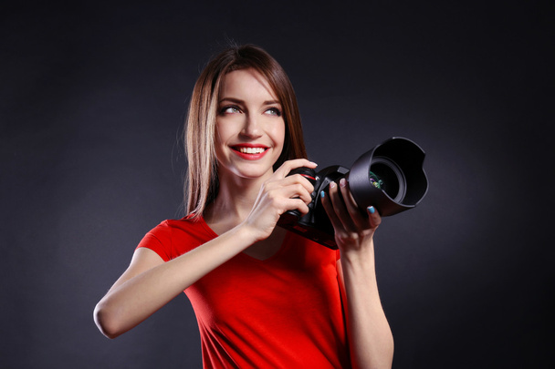 Young female photographer taking photos on black background - Zdjęcie, obraz