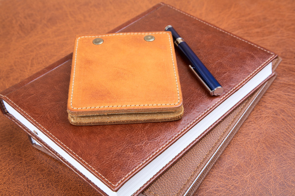 Leather organizers and pen on a textural background - 写真・画像