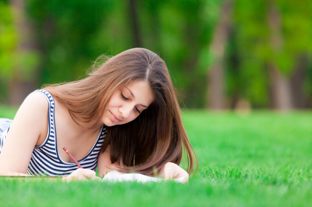 Tyttö kirjan kanssa vihreällä ruoholla
 - Valokuva, kuva