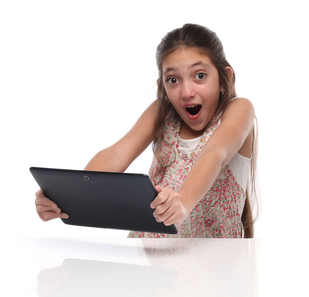 Έκπληκτος προ-έφηβος κορίτσι με έναν υπολογιστή δισκίο. - Φωτογραφία, εικόνα