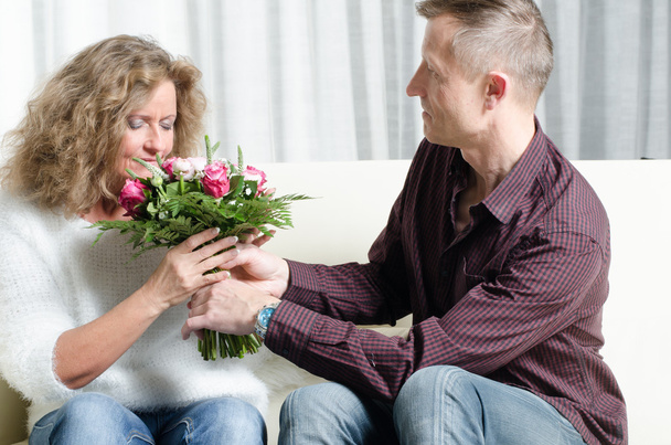 Mann schenkt Frau einen Blumenstrauß - sie riecht. - Foto, Bild