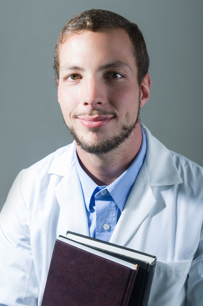 Closeup portrait of handsome young doctor holding books - Foto, Imagen
