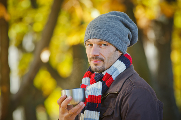 Man drinks tea in autumn park - Фото, изображение