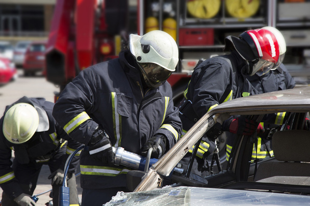 пожежники з пневматичними ножицями відкривають двері автомобіля
 - Фото, зображення