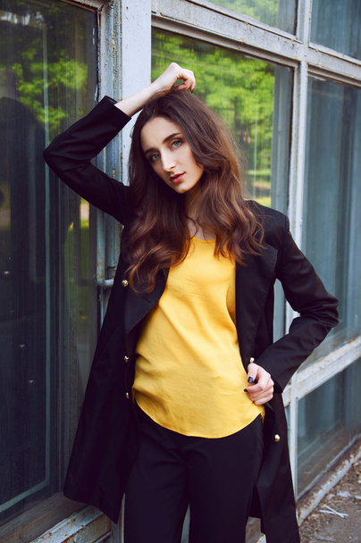 Retrato de mujer joven en gabardina negra y blusa amarilla
 - Foto, Imagen