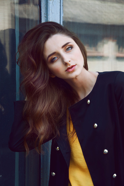 Young woman portrait in black trenchcoat and yellow blouse - Photo, Image