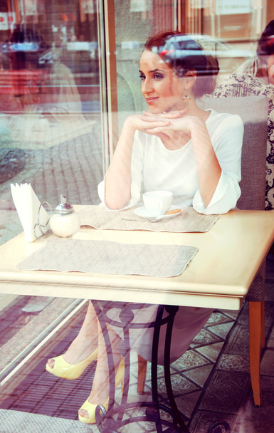 お茶を飲むカフェに座って美しい優雅なブロンド。ビューの木 - 写真・画像