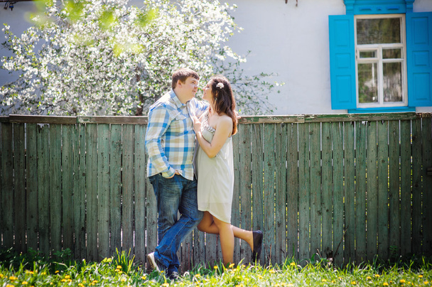 milující pár stojící nedaleko plotu v jarní slunečný den - Fotografie, Obrázek