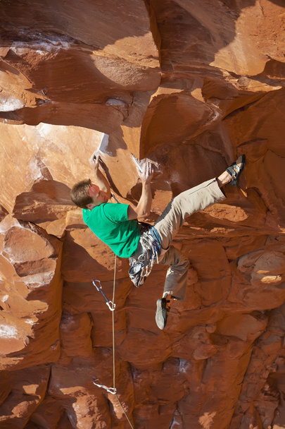 rock klimmer klampt zich vast aan een steile klif. - Foto, afbeelding
