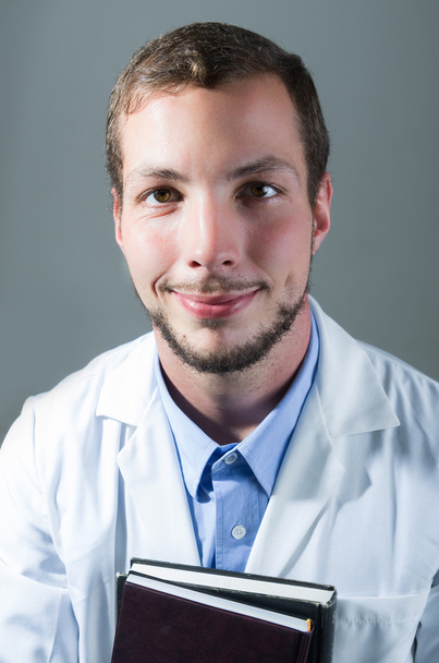 Closeup portrait of handsome young doctor holding books - Foto, Imagen