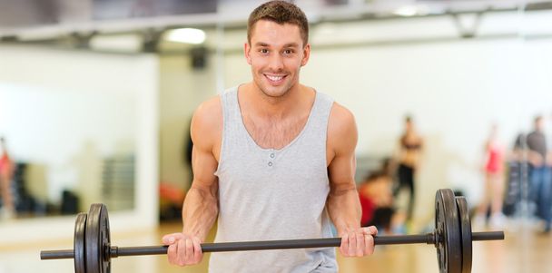 smiling man with barbell in gym - Фото, зображення