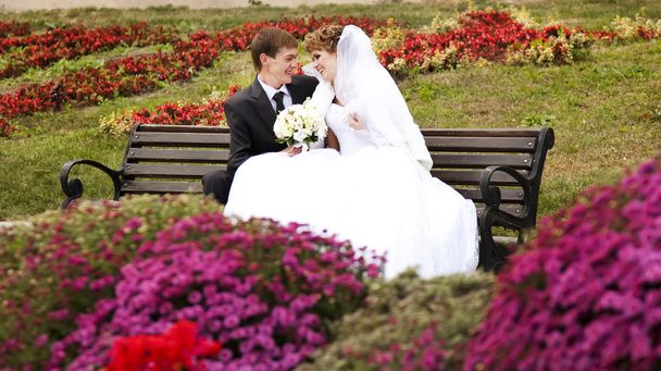 Young just married couple sitting close to each other on bench i - Photo, Image