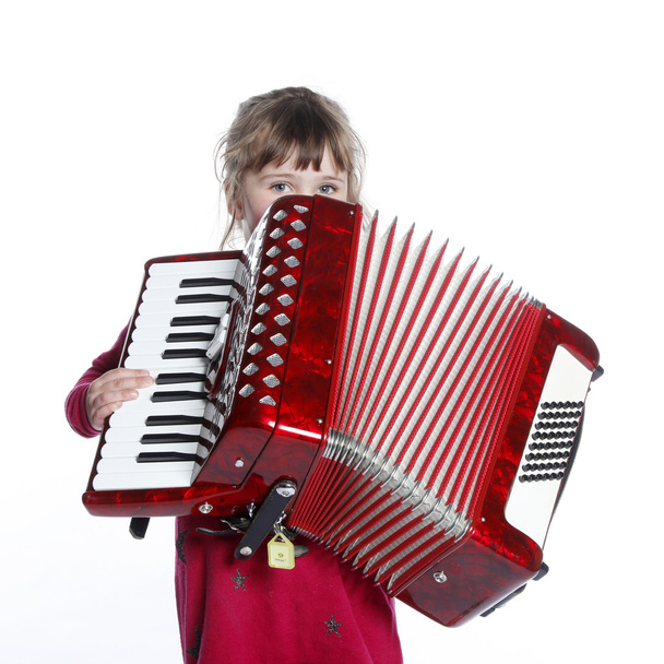 zeer jong meisje met accordeon in studio - Foto, afbeelding
